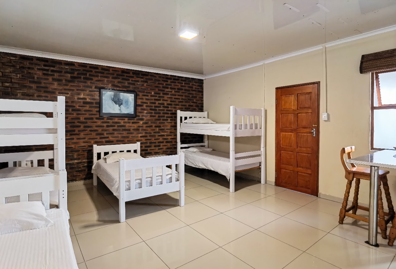 6-sleeper dorm room with bunk beds and brick wall design in Ballito Backpackers' semi self-catering room