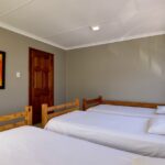 Spacious 6-sleeper dorm room with wooden bunk beds in Ballito Backpackers.